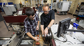 Instructor guiding a student with equipment in the lab