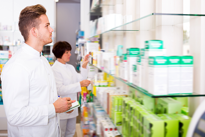 A pharmacy technician looking at a shelf of medications