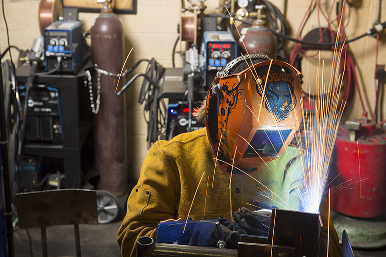 Student welding a project with sparks flying