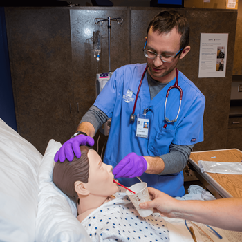 Male student works with simulation equipment in the Nursing program