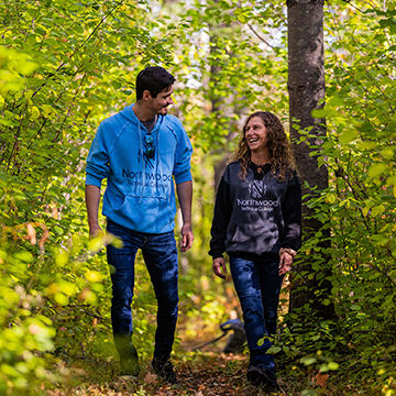 Two students walking down a path in the woods