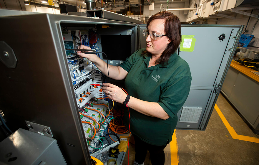 An automated packaging student working with equipment in the lab