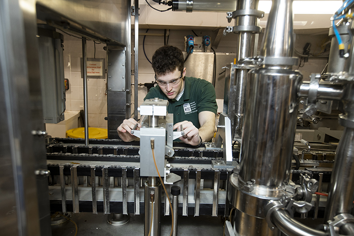 An automated packaging student working with equipment in the lab