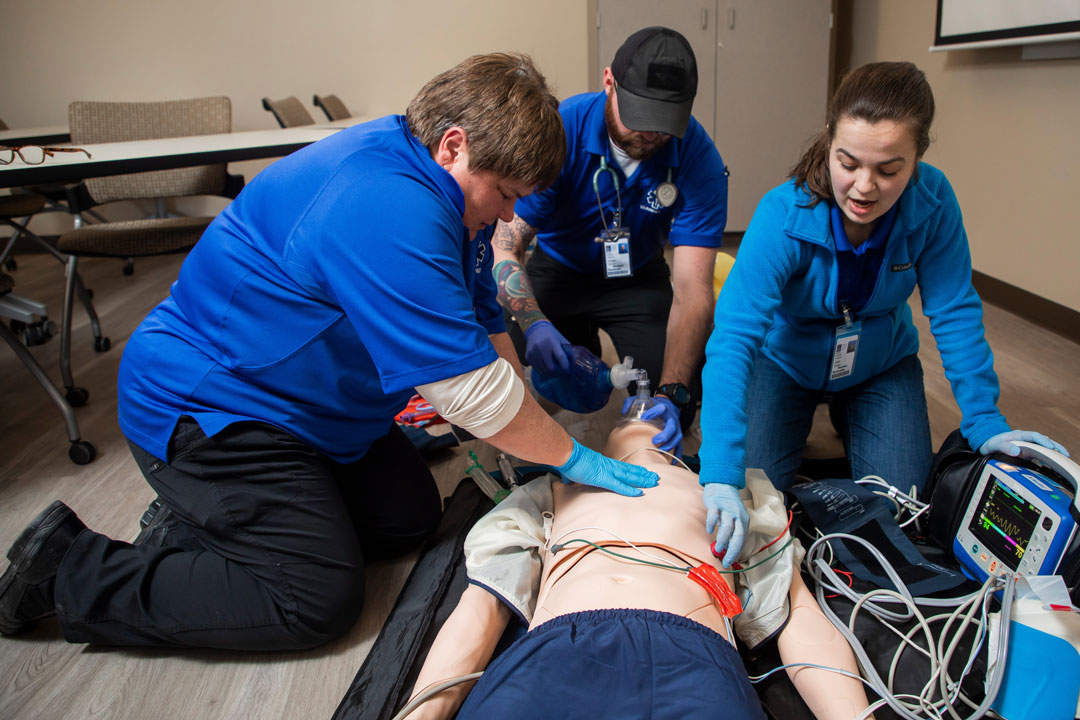 Three students practicing life saving skills on training mannequin
