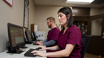 Two pharmacy technician students working on computers