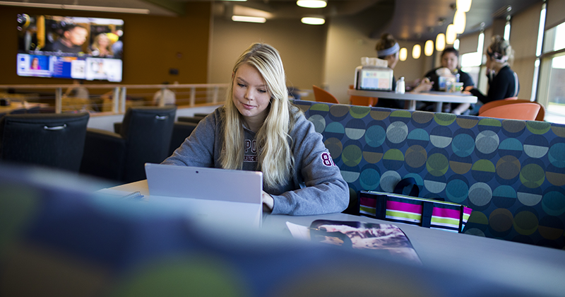 Student on campus reading at a booth in the student HUB