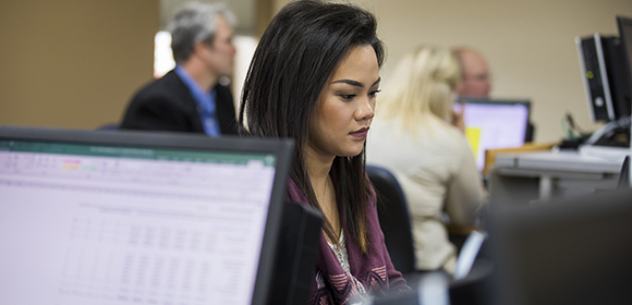 Woman works on finance on a computer in a standard business classroom