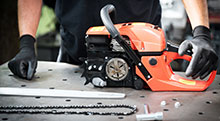 An outdoor power equipment technician repairing a chainsaw