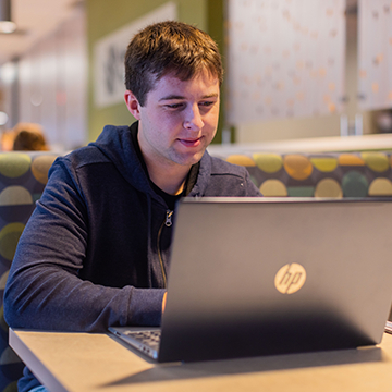 Student sitting at a laptop in commons area