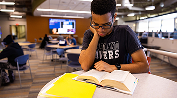 Student sitting at a table reading a textbook