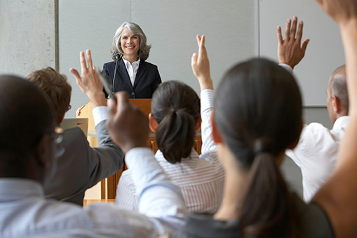 Continuing Education classroom with instructor at podium and students raising their hands