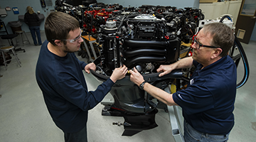 A marine repair student and teacher looking at parts