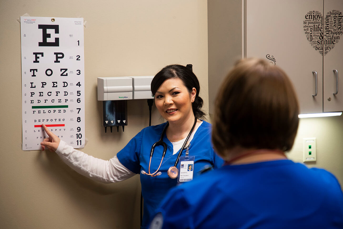 A healthcare student pointing at an eye exam chart