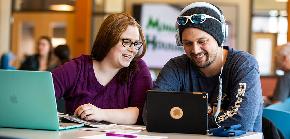 Two students hanging out and looking at a computer