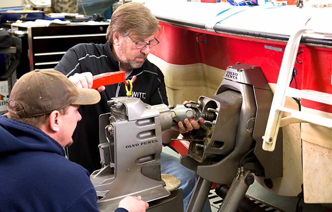 An instructor helping a student while working on a boat