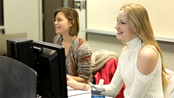 Two students in the classroom sitting at computers