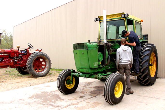 Students working on a tractor outside of the garage