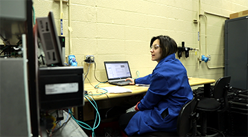 A student wearing a lab coat and working on a computer
