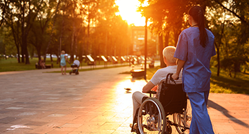 A Certified Nursing Assistant pushing an older adult in a wheel chair