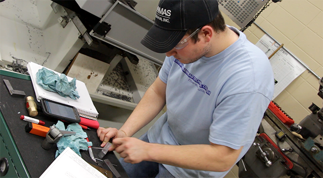 A student working intently with a machine part