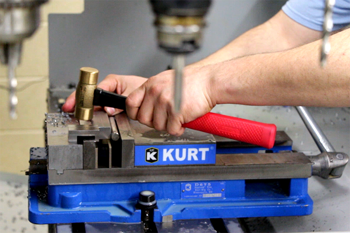 A student using a hammer to crush metal pieces