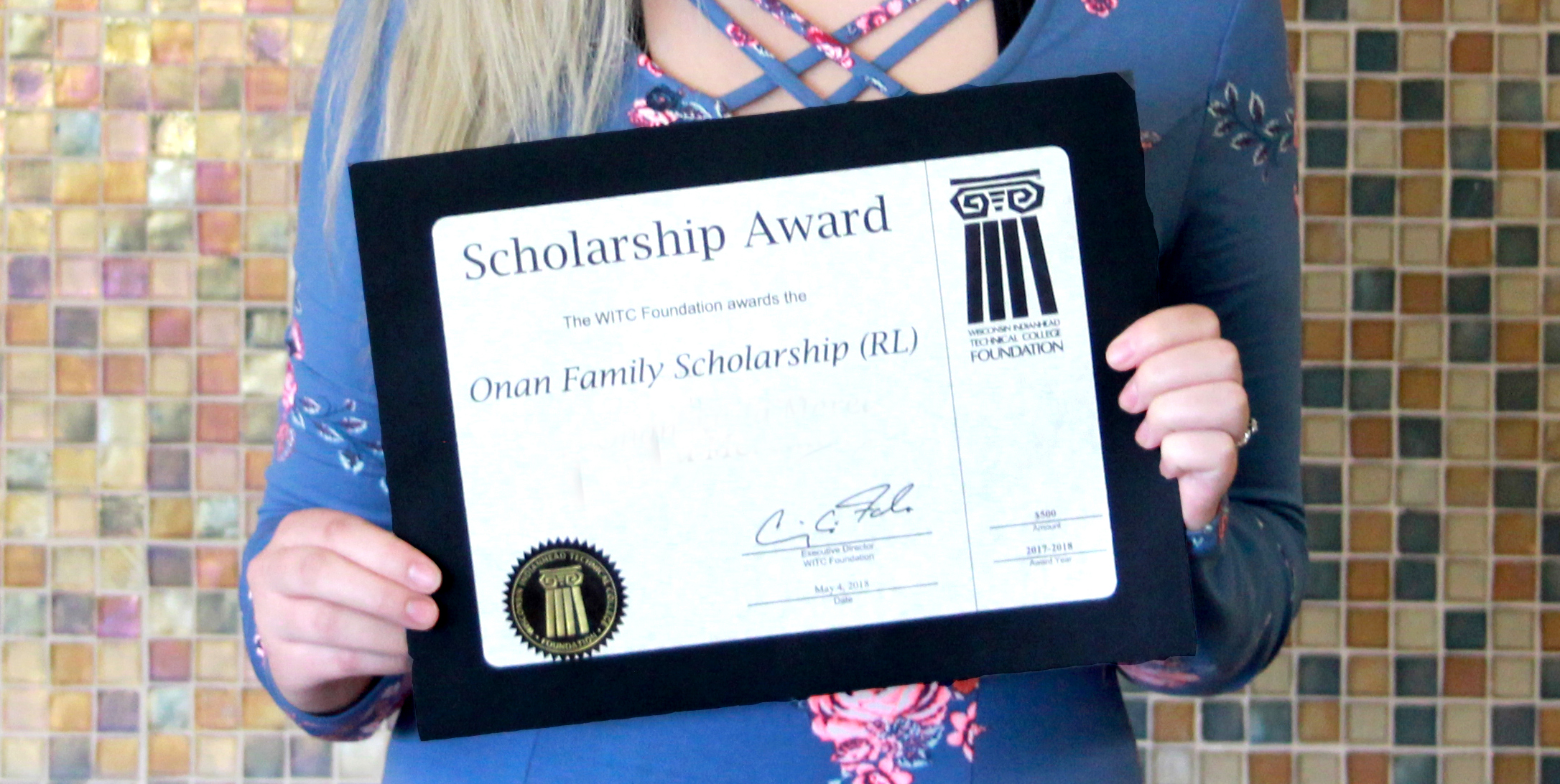 A student holding their scholarship award