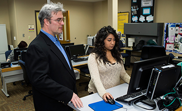 An instructor looking over a student's shoulder on a computer