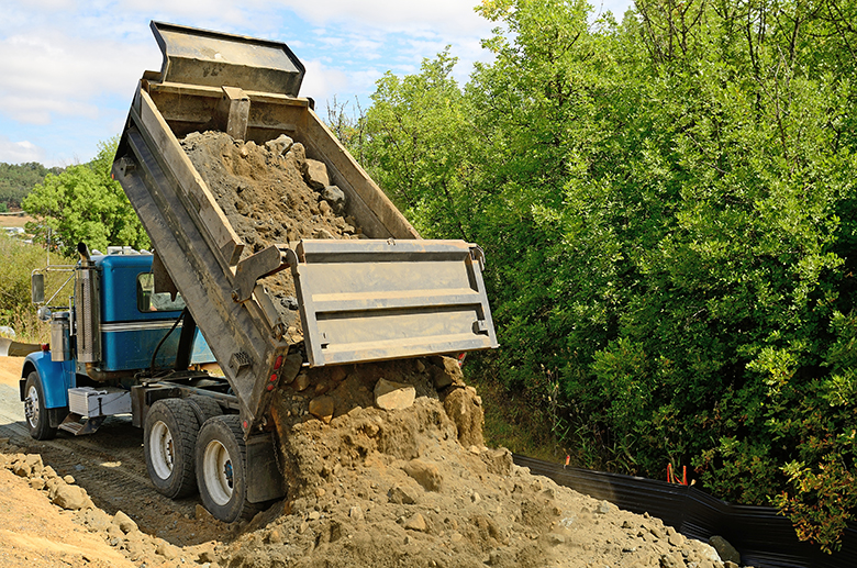 A dumptruck dumps its load of rock