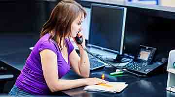 An office employee talking on the phone at a front desk
