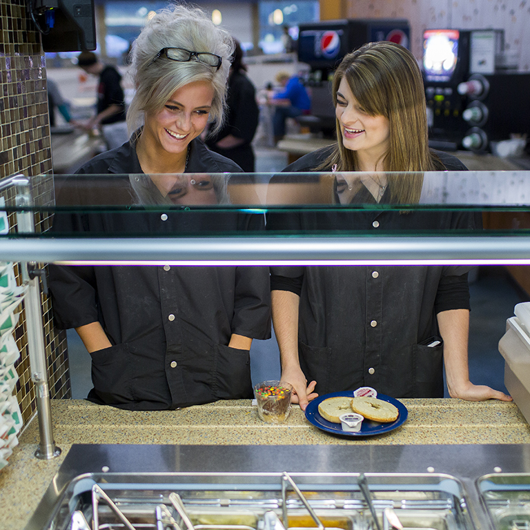 Two female WITC students in line at the cafeteria, selecting lunch from the salad bar.