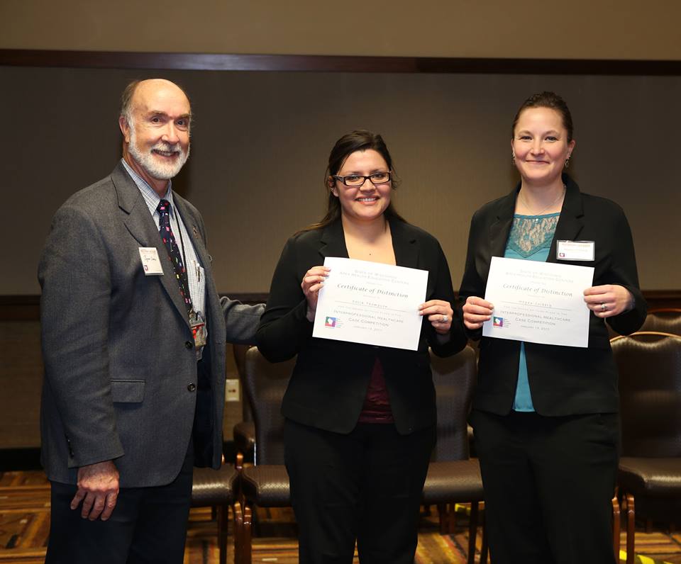Two nursing students holding their awards at the Interprofessional Healthcare Case Competition, pictured with executive director