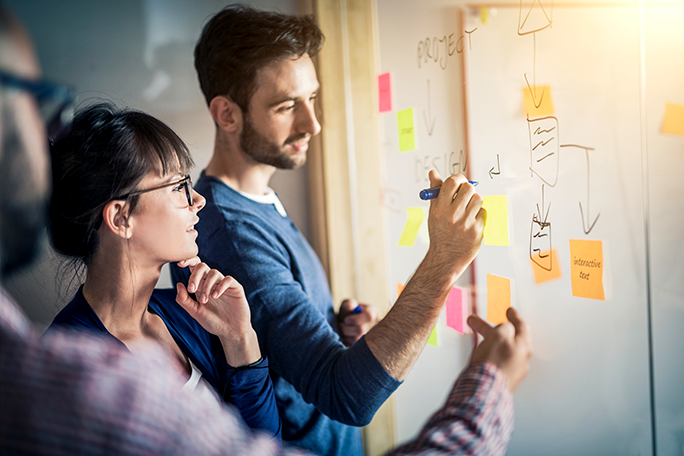 Two business professionals brainstorming with a marker board and post-it notes