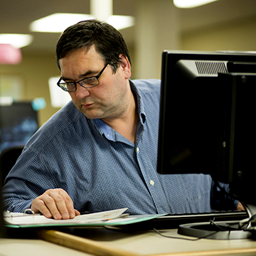 Student sitting at a computer and referencing a book