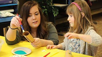 An early childhood education student making crafts with a young child