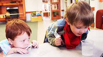 Two young children looking at a cup