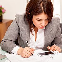 Student taking notes, cell phone on table