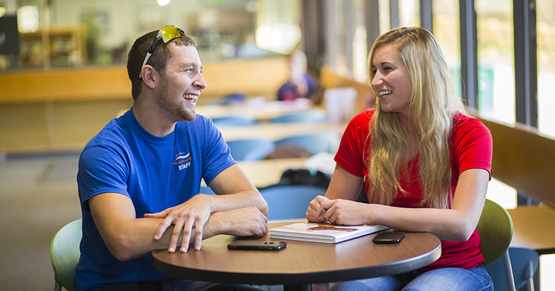 Students sitting and laughing in the lounge at a high top table