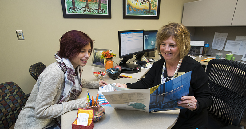 Student sits with admissions advisor looking through the view book 