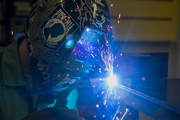 A welding student in the shop working with the tools of the trade