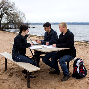 Group of students sitting by Lake Superior at a picnic table Group of students sitting by Lake Superior at a picnic table