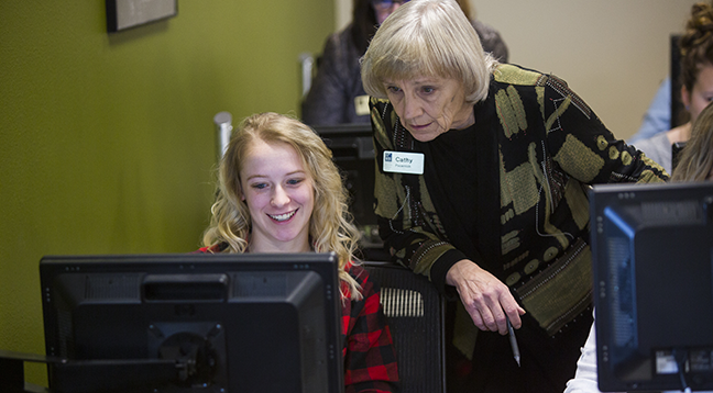 An instructor looking over a student's shoulder on a computer