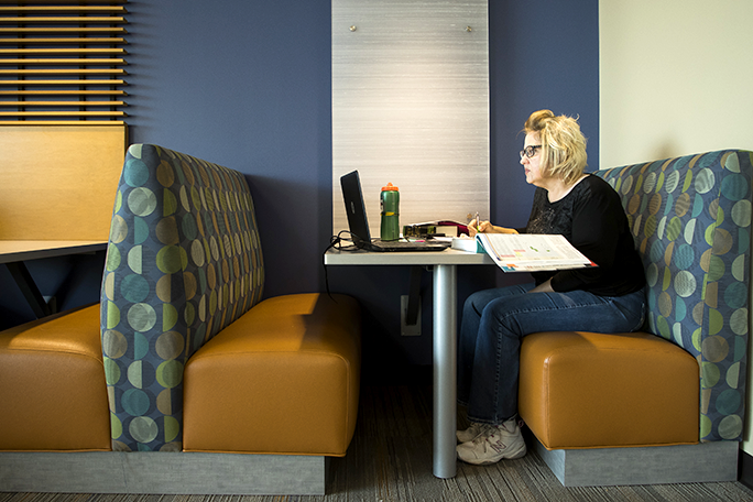 A person sitting in a booth studying with books and a laptop