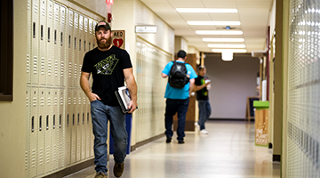 Student walking down a hallway with lockers