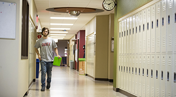 A student walking down a hall with lockers