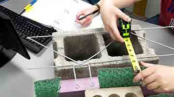 Hands on image of students working with building materials and measuring