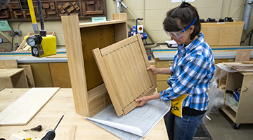 A student working on the production of a cabinet