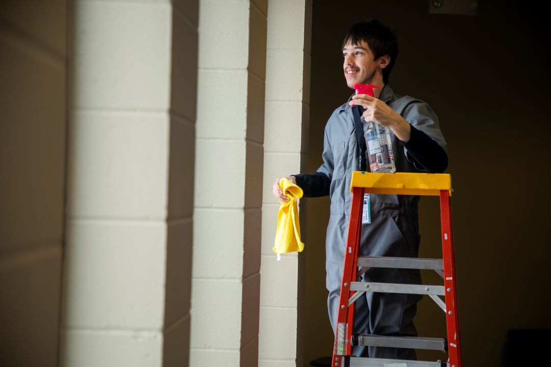 student smiling while washing window