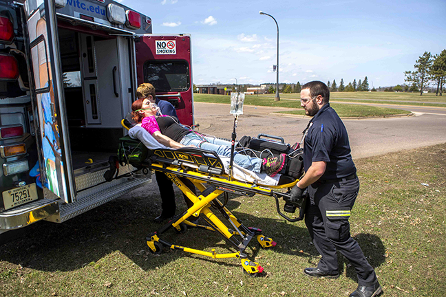 Advanced EMT students practicing loading a stretcher into an ambulance