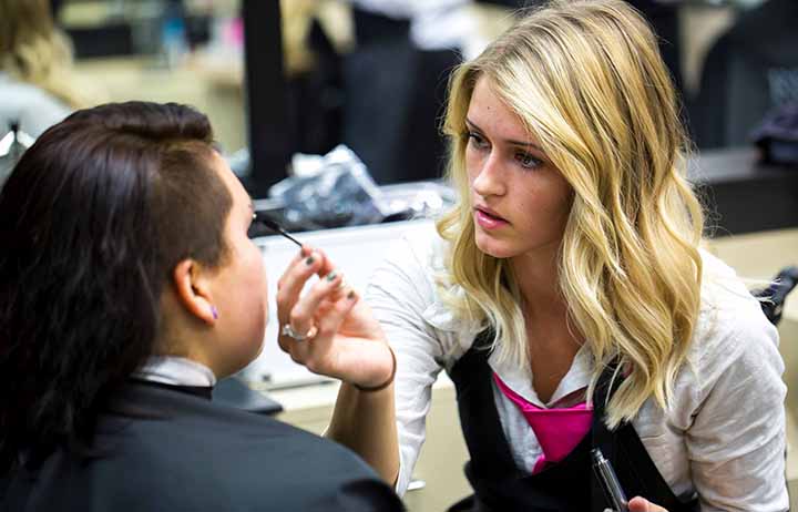 Cosmetology student applying mascara to a client