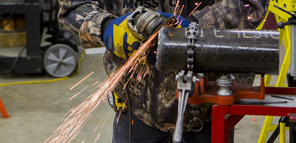 Man grinds a pipe end as part of a customized training class in a WITC classroom